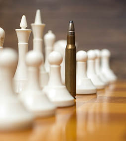 Closeup photo of bullet in row of white chess pieces on wooden board  Concept of military power