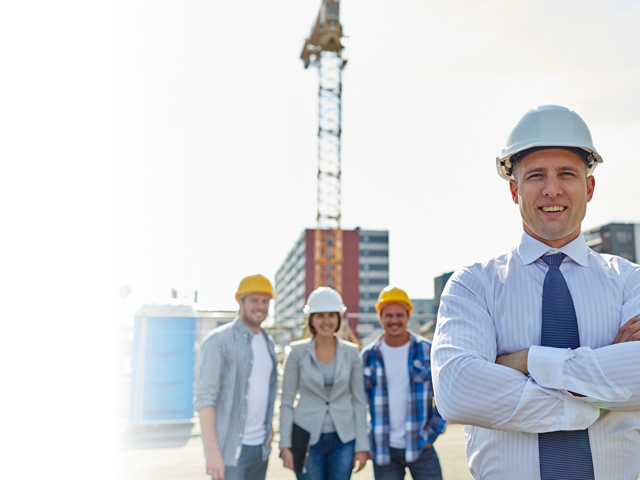 business, building, teamwork and people concept - group of smiling builders and architect in hardhats at construction site