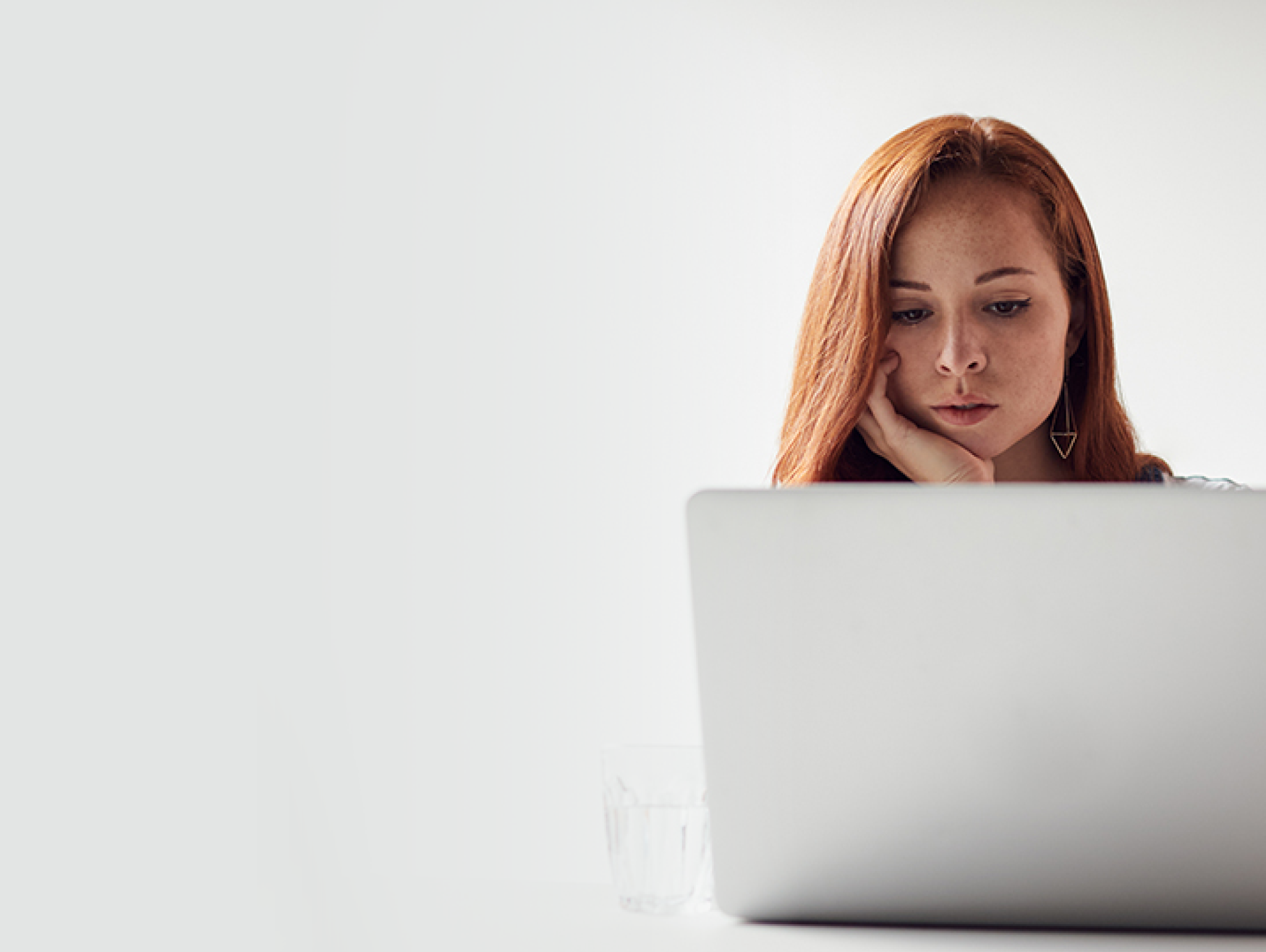 Casually Dressed Young Businesswoman Working On Laptop At Desk In Modern Workplace