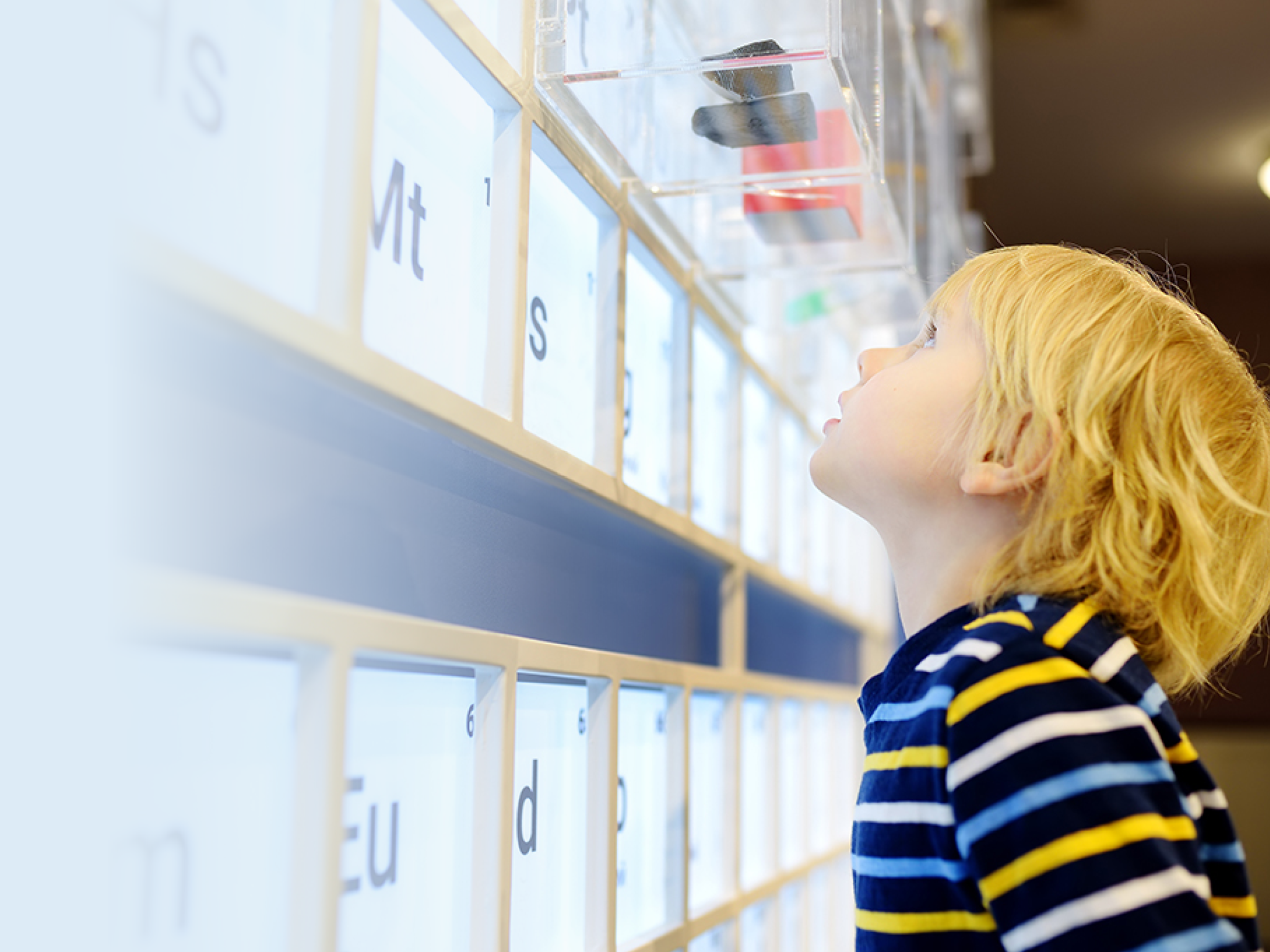Little caucasian boy is looking at the exposition in the scientific museum. Child is interested in chemistry. Education and entertainment for children. Entertainment for families with preschooler kids